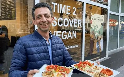 Gospodarz Niedaleko Damaszku z talerzami syryjskich dań przed restauracją